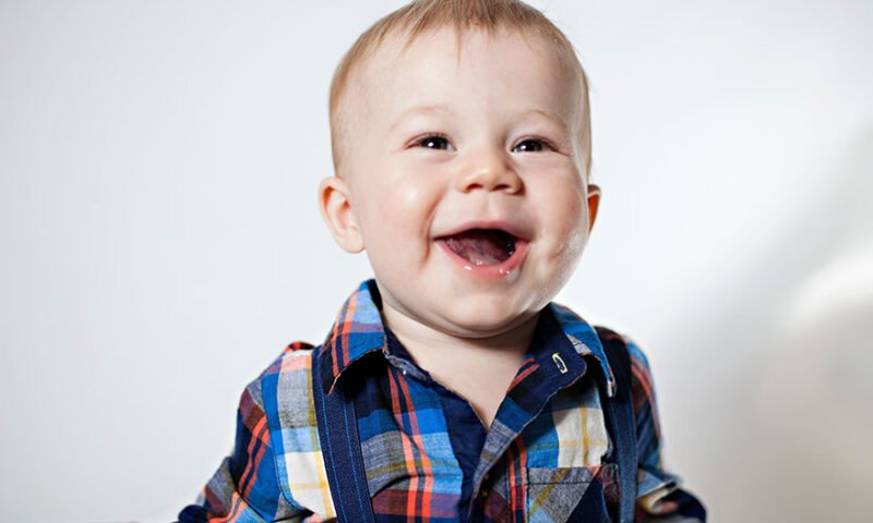 bebê sorrindo com camisa xadrez - marcos do desenvolvimento infantil